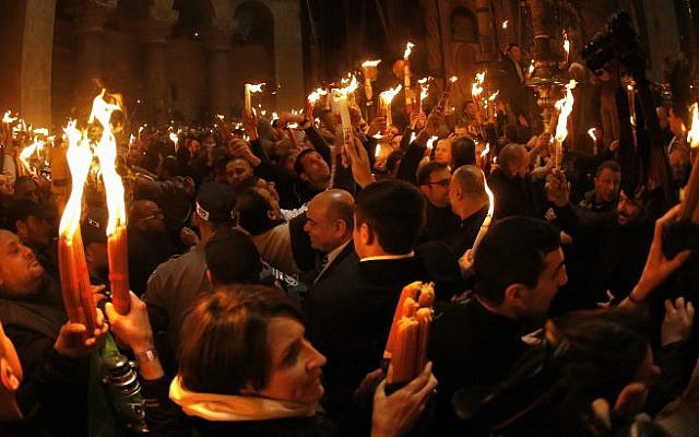 Christian Orthodox worshipers light candles from the "Holy Fire" as thousands gather in the Church of the Holy Sepulcher, traditionally believed to be built on the site where Jesus was crucified, buried and resurrected, in Jerusalem’s Old City, on April 11, 2015. (photo credit: AFP/Thomas Coex)