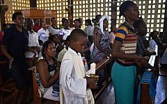A young altar server holds a candle during a Easter service at the Catholic cathedral in Garissa on April 5, 2015, mourning the country's worst ever massacres, the killing of almost 150 people in an attack on a university by Somalia's Shabab Islamists that occurred on April 2 at Garissa's University. (photo credit: AFP/Carl De Souza)
