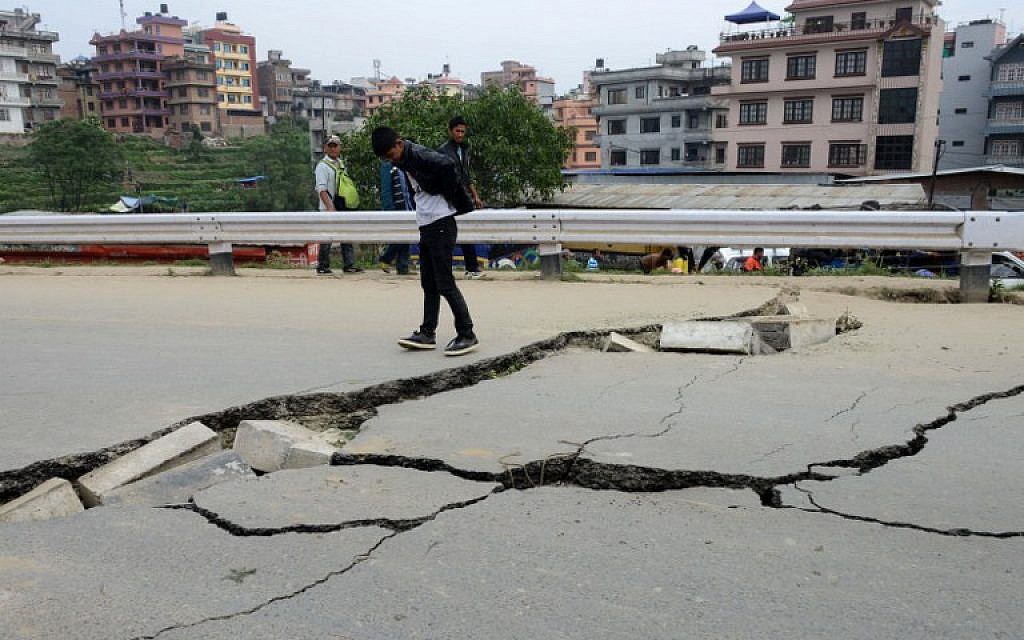 Nepalese residents walks past road damage following an earthquake in Kathmandu on April 26, 2015. (photo credit: AFP PHOTO / PRAKASH MATHEMA)