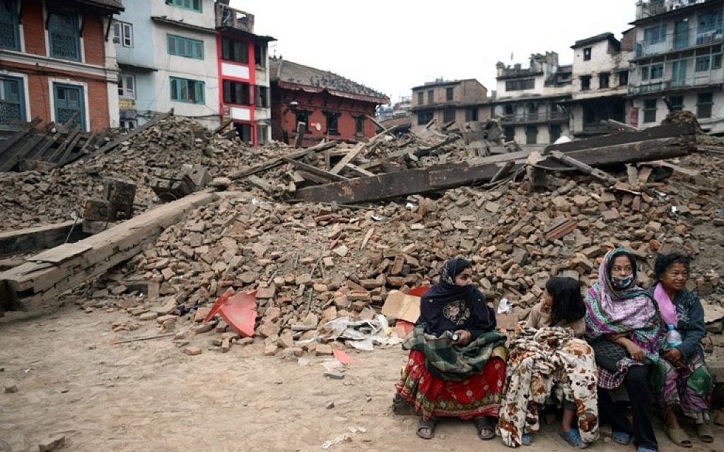 Nepalese residents sit near buildings severely damaged by an earthquake in Kathmandu on April 26, 2015. (photo credit: AFP PHOTO / PRAKASH MATHEMA)