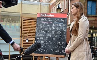 An employee of Ladbrokes betting company is interviewed by a member of the media as she stands by a blackboard with the odds of the sex and name of the upcoming royal baby outside the Lindo Wing of St Mary's hospital in central London where Catherine, Duchess of Cambridge is expected to give birth to her second child. (Photo credit: AFP/ LEON NEAL)