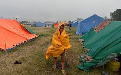 A Nepalese residents walks during a downpour at a relief camp for earthquake survivors in Kathmandu on May 23, 2015. (AFP/ISHARA S. KODIKARA)