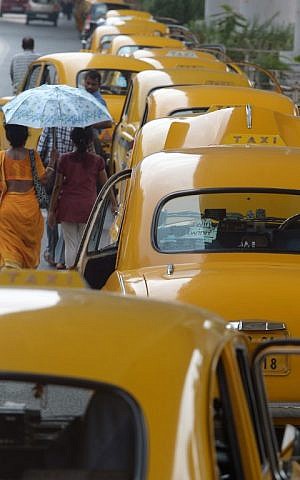 Indian pedestrians walk past parked taxis in Kolkata on May 25, 2015.  In the eastern city of Kolkata, taxi unions have urged drivers to stay off the roads between 11am and 4pm because of the heat. (Dibyangshu Sarkar/AFP)