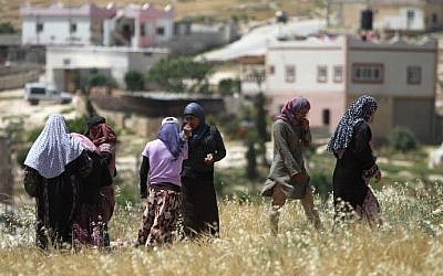 Palestinian women walk in a field on April 21, 2015 in the West Bank village of Ad-Deirat Rifaiyya, where more than half of the homes are built on land owned by the villagers but without Israel's approval leaving them under threat of demolition by Israeli bulldozers. (Photo credit: Hazem Bader/AFP)