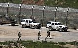 Israeli soldiers walk past vehicles of the United Nations Disengagement Observer Force (UNDOF) near the town of Majdal Shams, on the Golan Heights, April 27, 2015. (AFP/Jalaa Marey)