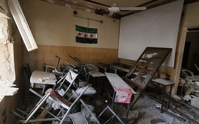 A pre-Baath Syrian flag, now used by the Syrian opposition, hangs in a heavily damaged classroom after a barrel bomb hit a school in Syria's northern city of Aleppo Saif al-Dawla district, where control is split between the Syrian regime and opposition, on May 3, 2015. (AFP PHOTO / BARAA AL-HALABI) A pre-Baath Syrian flag, now used by the Syrian opposition, hangs in a heavily damaged classroom after a barrel bomb hit a school in Syria's northern city of Aleppo Saif al-Dawla district, where control is split between the Syrian regime and opposition, on May 3, 2015. (AFP PHOTO / BARAA AL-HALABI)