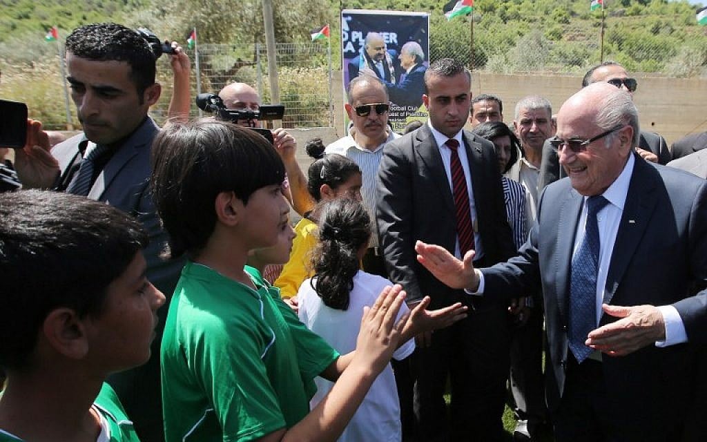 FIFA president Joseph Blatter (R) shakes hands with Palestinian children during his visit to the sports club in the village of Dura al-Qaraa, near the West Bank city of Ramallah, on May 20, 2015.  (AFP PHOTO / ABBAS MOMANI)