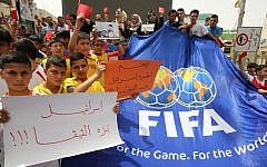 Palestinian youth hold red cards and placards reading in Arabic, 'Israel out of FIFA,' during a demonstration against the Israel Football Federation in the West Bank city of Hebron, on May 28, 2015. (AFP photo/Hazem Bader)