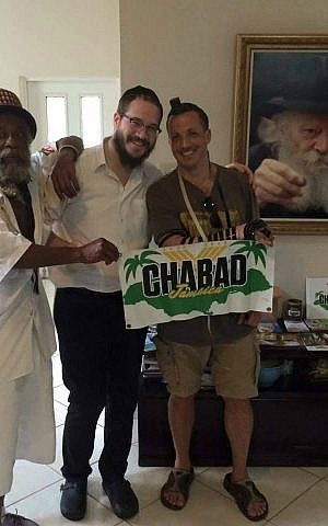 Rabbi Yaakov Raskin (center) instructs men on how to put on tefillin at Chabad House in Montego Bay, Jamaica. (Courtesy)