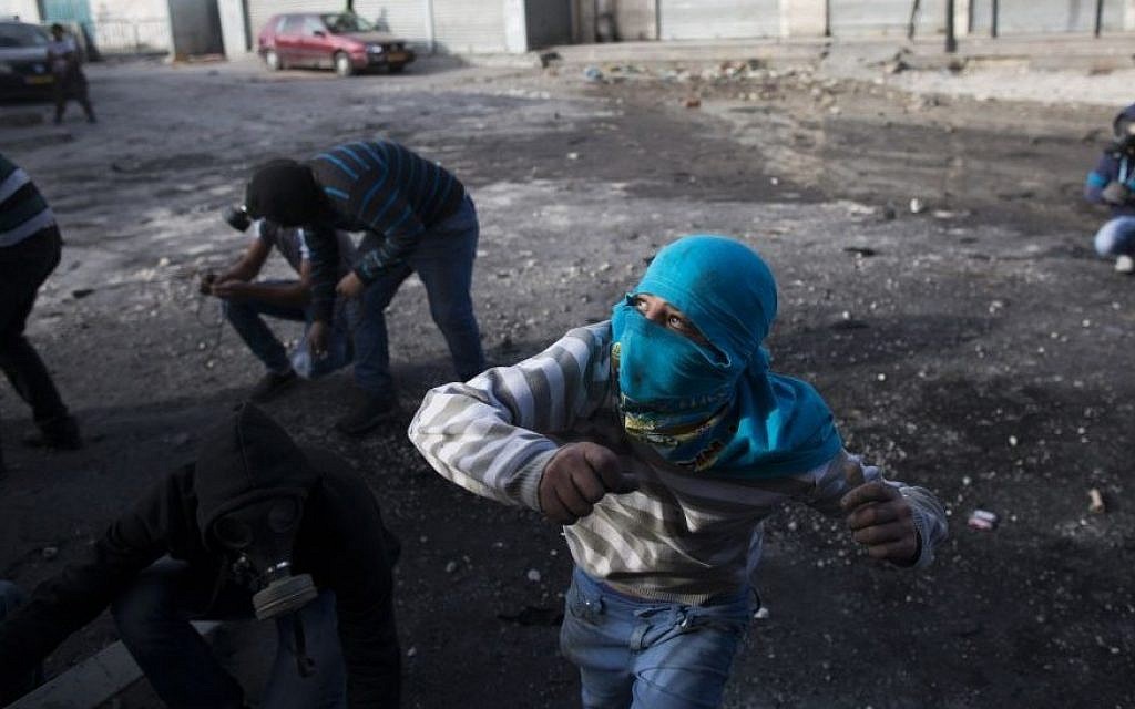 Palestinian youth throw stones during clashes with Border Police in the Shuafat refugee camp in Jerusalem following Friday prayers on November 7, 2014. (Yonatan Sindel/Flash90) Palestinian youth throw stones during clashes with Border Police in the Shuafat refugee camp in Jerusalem following Friday prayers on November 7, 2014. (Yonatan Sindel/Flash90)
