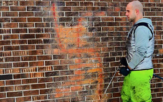 Corey Fleischer removes a five foot-tall swastika on the side of a house in Montreal. (photo credit: courtesy)