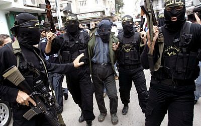 Palestinian Islamic Jihad masked gunmen hold up their guns as they display one of two men whom they alleged were Palestinian collaborators for Israel, in Gaza City, November 5, 2006. (AP/Khalil Hamra/File)