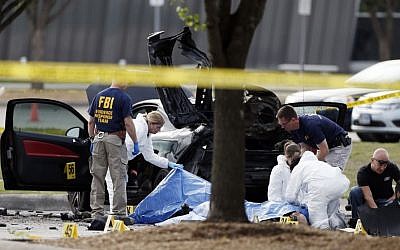 FBI crime scene investigators document the area around two deceased gunmen and their vehicle outside the Curtis Culwell Center in Garland, Texas, Monday, May 4, 2015. (Photo credit: AP/Brandon Wade)