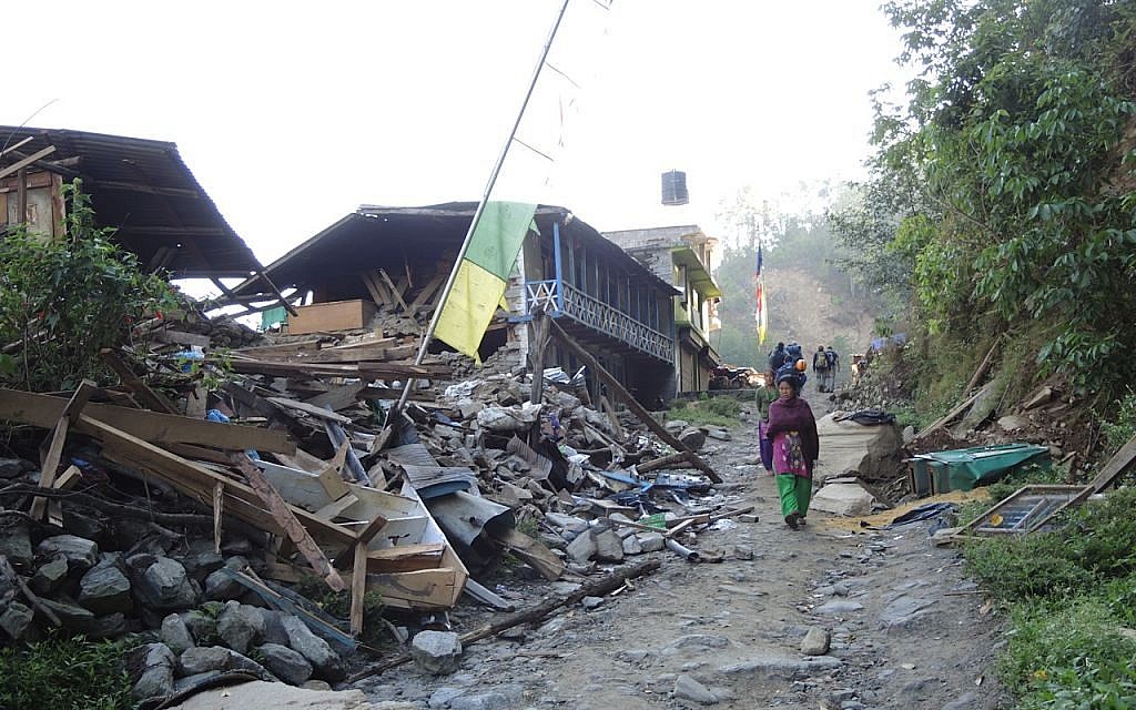 A woman walks beneath a strand of prayer flags in the demolished village of Topani, in the hard-hit Sidhulpalchowk district, seven hours away from Kathmandu, Nepal. May 2015. (photo credit: Melanie Lidman / Times of Israel)