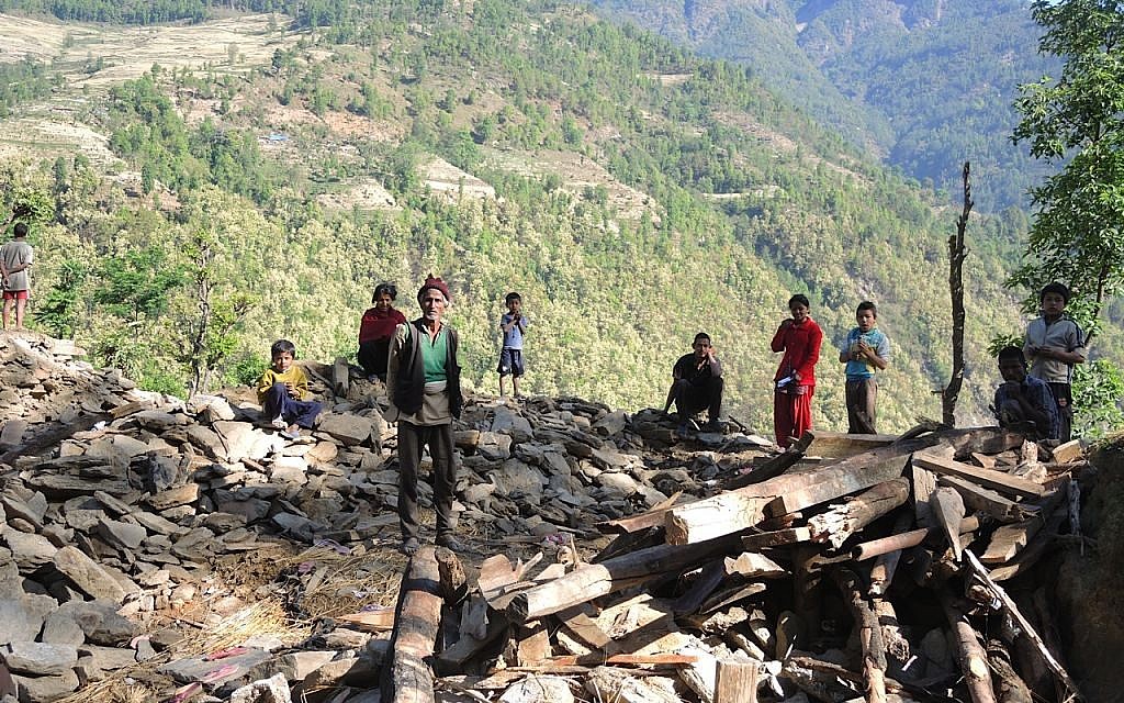 On our way to set up a medical clinic, a man named Shista (in the hat) begged us for food and medicine, but the porters had already carried the medicine ahead to the site of the clinic. Shista lost three family members, including his daughter. Here, he stands with his family on the ruins of their home in the demolished village of Topani, in the hard-hit Sidhulpalchowk district, seven hours away from Kathmandu, Nepal. May 2015. (photo credit: Melanie Lidman / Times of Israel)