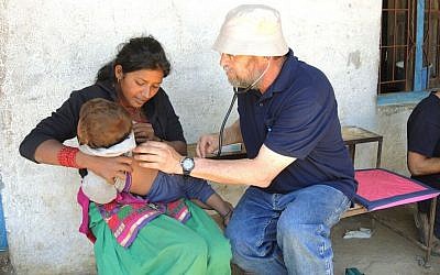 Dr. Asher Monser checks a reluctant toddler at the IsrAID mobile clinic in a village ten hours northeast of Kathmandu. (Photo credit: Melanie Lidman/Times of Israel)