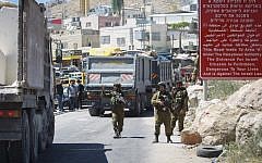 Israeli soldiers search Palestinians at a checkpoint in June 2014. (Photo credit: Hadas Parush/FLASH90)