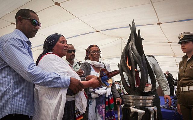 Members of the Ethiopian Israeli community light a torch at state ceremony in remembrance of Ethiopian Jews who died on their journey to Israel, Mount Herzl, Jerusalem, May 17, 2015. (Gil Yochanan/POOL)
