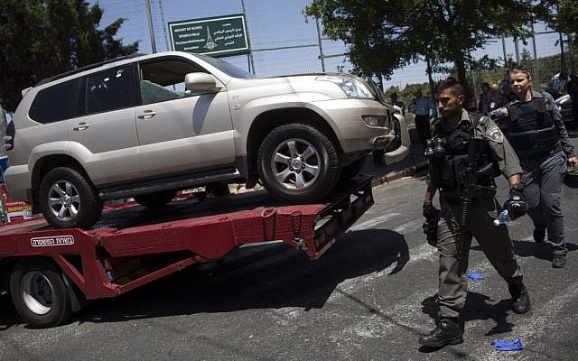 Policemen walk past the jeep used by the suspect to run over a group of border policemen in the Arab neighborhood of A-Tur in East Jerusalem, on May 20, 2015. (Yonatan Sindel/Flash90)