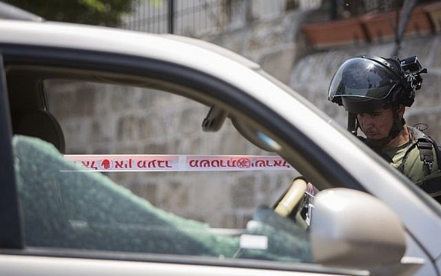 A policeman looks at the car used by the suspect to run over a group of border policemen in the Arab neighborhood of A-Tur in East Jerusalem, on May 20, 2015. (Yonatan Sindel/Flash90)