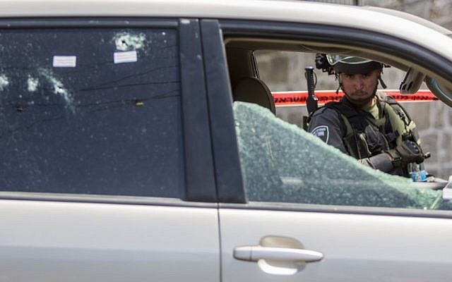 A policeman looks at the car used by the suspect to run over a group of border policemen in the Arab neighborhood of A-Tur in East Jerusalem, on May 20, 2015. (Yonatan Sindel/Flash90)