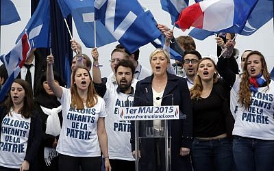 France’s far-right National Front president Marine Le Pen, center, surrounded by supporters, sings the French National Anthem after her speech at Opera Plaza during the annual May Day march, in Paris, May 1, 2015. (photo credit: AP Photo/Francois Mori)