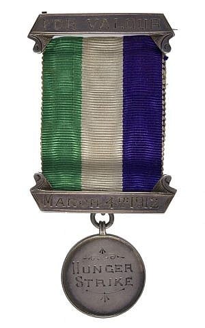 This hunger strike medal’s striped ribbon reflects the official colors -- green (hope), purple (dignity) and white (purity) -- of the -Women’s Social and Political Union. (courtesy) This hunger strike medal’s striped ribbon reflects the official colors -- green (hope), purple (dignity) and white (purity) -- of the -Women’s Social and Political Union. (courtesy)