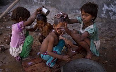 Two young girls bathe their siblings by a public tap on a hot summer day at Badshahpur, on the outskirts of New Delhi, India, Wednesday, May 27, 2015. Delhi recorded a maximum temperature of 42 degrees Celsius on Wednesday. In southern India, hundreds of people have died since the middle of April as soaring summer temperatures scorch the country, officials said Tuesday. (AP Photo/Saurabh Das)