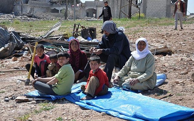 File: In this picture taken on Saturday April 18, 2015, a displaced Kurdish family sit in the open air field near their house which was destroyed during the battle between the US backed Kurdish forces and the Islamic State fighters, in Kobani, north Syria. (AP/Mehmet Shakir)