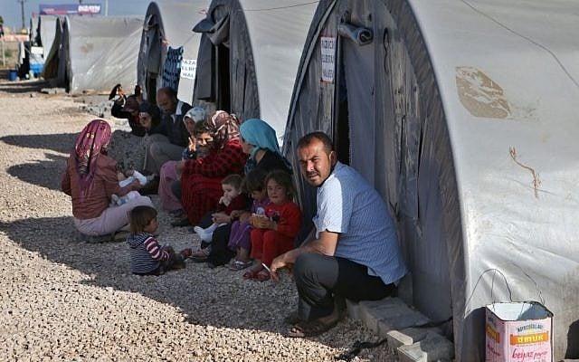 In this picture taken on Monday, April 20, 2015, Kurdish refugees sit outside their tents at the Arin Mirxan refugee camp, in Suruc town, Turkey. (AP/Hussein Malla)