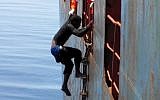 Dramatic footage emerged Tuesday May 5, 2015, filmed by a crew member, showing a Mediterranean Sea rescue of migrants on a sinking rubber boat desperately clambering up ropes and a ladder from the cargo ship Zeran that came to their aid on May 3, 2015, in the sea between Libya and Sicily. Five bodies were recovered and were brought ashore Tuesday along with the migrant survivors to the port in Catania, Sicily, Italy. (photo credit: AP)
