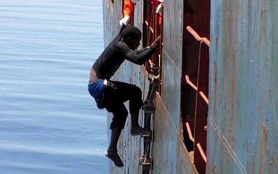 Dramatic footage emerged Tuesday May 5, 2015, filmed by a crew member, showing a Mediterranean Sea rescue of migrants on a sinking rubber boat desperately clambering up ropes and a ladder from the cargo ship Zeran that came to their aid on May 3, 2015, in the sea between Libya and Sicily. Five bodies were recovered and were brought ashore Tuesday along with the migrant survivors to the port in Catania, Sicily, Italy. (photo credit: AP)