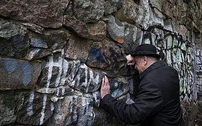 Shmuel Levin, chairperson of the Jewish religious community of Vilnius and Lithuania, leans against a wall of the power substation built of tombstones from a Jewish cemetery in Vilnius, Lithuania, May 13, 2015 (AP/Mindaugas Kulbis)