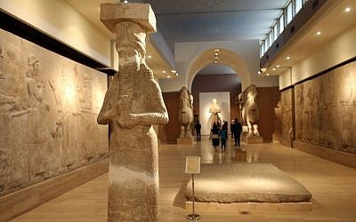 People observe ancient artifacts at the Iraqi National Museum on March 15, 2015 after its reopening in the wake of the recent destruction of Assyrian archaeological sites by the Islamic State group in Mosul, as they visit the museum in Baghdad. (photo credit: Karim Kadim/ AP)