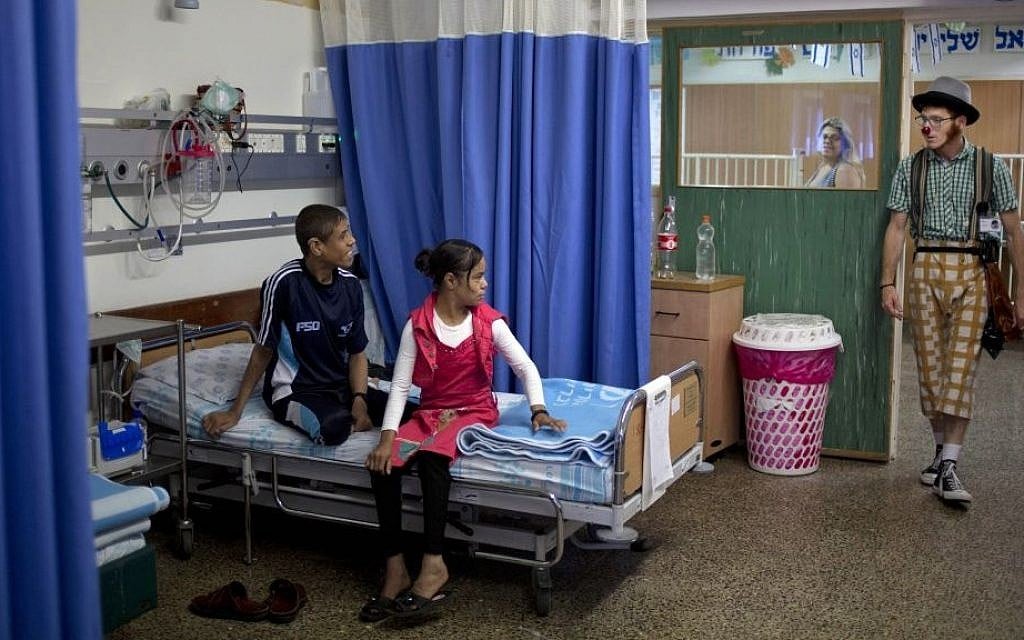 Palestinian siblings Ahmed, right, and Hadeel Hamdan, center, watch medical clown who goes by the name 'Juhl' at the Rambam Health Care Campus in Haifa, Israel, May 13, 2015 (AP/Ariel Schalit)