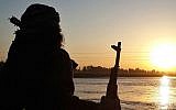 ILLUSTRATIVE: An Islamic State fighter holds his AK-47 machine gun as he stands guard on the bank of the Euphrates River in Raqqa, Syria. (Militant website via AP)