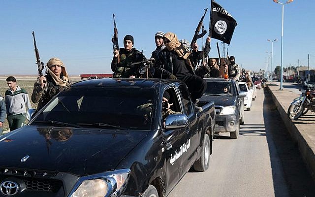 Islamic State fighters pass by a convoy in the town of Tel Abyad in northeast Syria, May 4, 2015. (Jihadist website via AP)