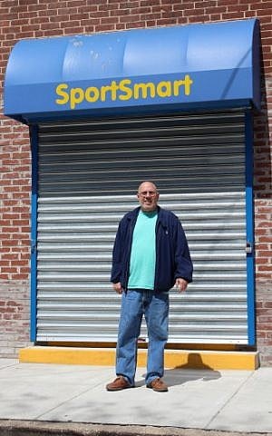 Sports Mart co-owner Marc Levy stands outside his store a day and a half after looters stole more than $1 million in merchandise, April 29, 2015. Although the store’s name is Sports Mart, the sign here has a different spelling. (photo credit: JTA/Hillel Kuttler)