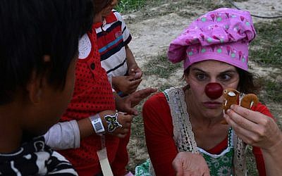 An Israeli medical clown entertains a Nepalese earthquake victim during a visit to a makeshift army camp in Kathmandu on May 6, 2015 (photo credit: AFP/PRAKASH MATHEMA)