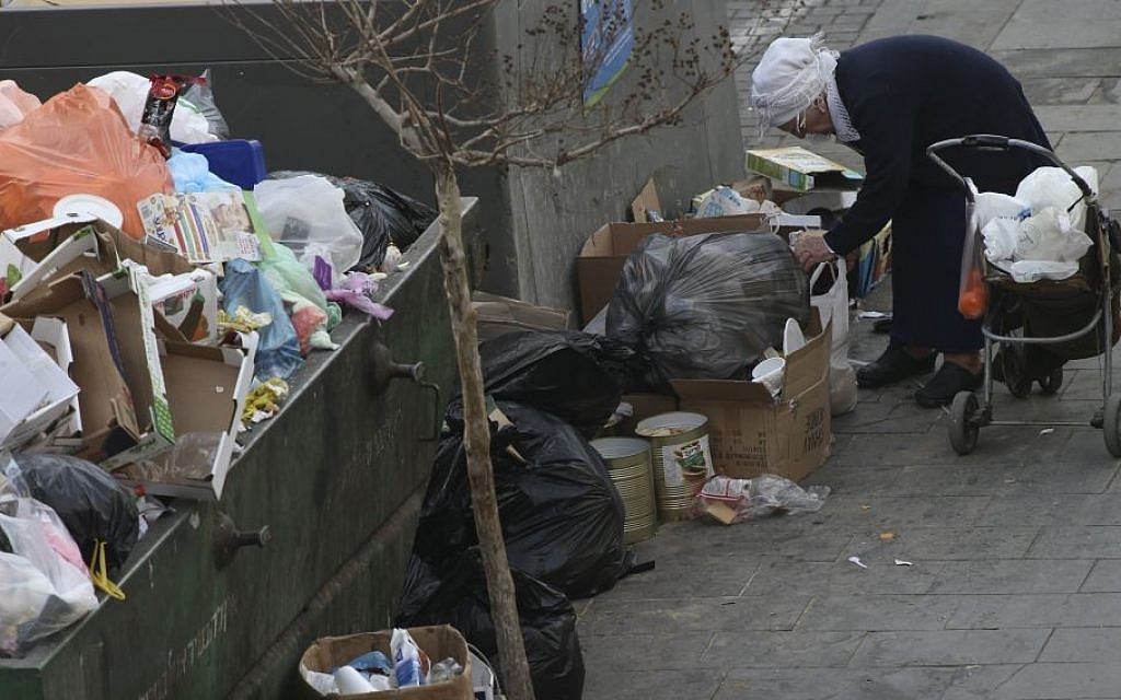 An Israeli woman searches for objects in a garbage container in Jerusalem, April 2, 2015 (photo by Nati Shohat/Flash90)