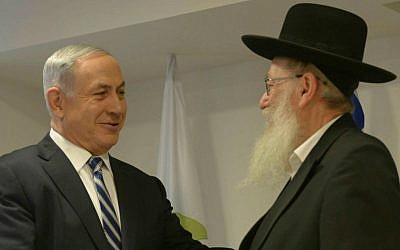 Prime Minister Benjamin Netanyahu (L) congratulates then-incoming Deputy Health Minister Yaakov Litzman at the Health Ministry in Jerusalem, on May 20, 2015. (Amos Ben Gershom/ GPO/Flash90)