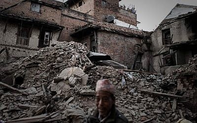 A pedestrian walks past destroyed houses in the village of Satungal on the outskirts of Kathmandu on May 5, 2015, following a 7.8 magnitude earthquake which struck the Himalayan nation of Nepal on April 25 (photo credit: AFP/Philippe Lopez) 