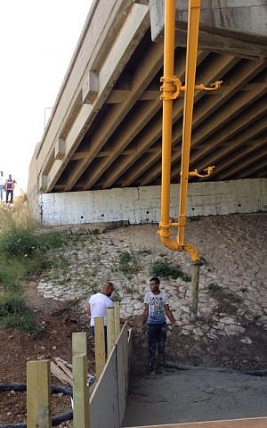 The cement truck poured the CLSM through the chute, over the site of the overpass, into the crevice under the bridge (Jessica Steinberg/Times of Israel)