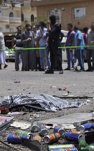 Human remains are seeing covered with a cloth as Egyptian bystanders look at the scene where assailants attempted to carry out a suicide bomb attack on June 10, 2015,  in the Karnak temple in Luxor. (AFP PHOTO / STR)