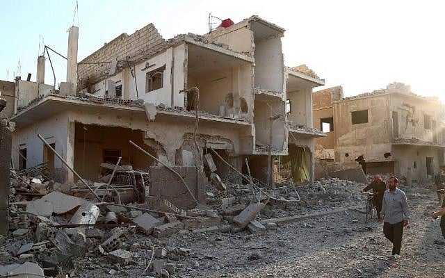Illustrative: Syrians walk past a building destroyed in a reported air strike by government forces on the rebel-held town of Douma, northeast of Damascus, on June 16, 2015. (AFP/Sameer Al-Doumy) Illustrative: Syrians walk past a building destroyed in a reported air strike by government forces on the rebel-held town of Douma, northeast of Damascus, on June 16, 2015. (AFP/Sameer Al-Doumy)