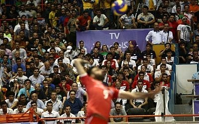 Iran's Adel Gholami serves the ball as a few women sit amid the fans during the volleyball World League pool B match between Iran and USA at Tehran's Azadi arena on June 19, 2015, in which Iran won 3-0 (AFP PHOTO / BEHROUZ MEHRI)