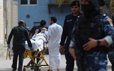 Kuwaiti emergency personnel pull a man on stretchers past security forces outside the Shiite Al-Imam al-Sadeq mosque after it was targeted by a suicide bombing during Friday prayers on June 26, 2015, in Kuwait City. (AFP)