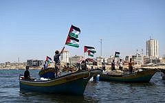 Illustrative: Palestinians wave flags as they ride boats in support of activists aboard a flotilla made up of four boats aimed at defying Israel's blockade of Gaza, at the seaport of Gaza City on June 28, 2015. (Mahmud Hams/AFP)