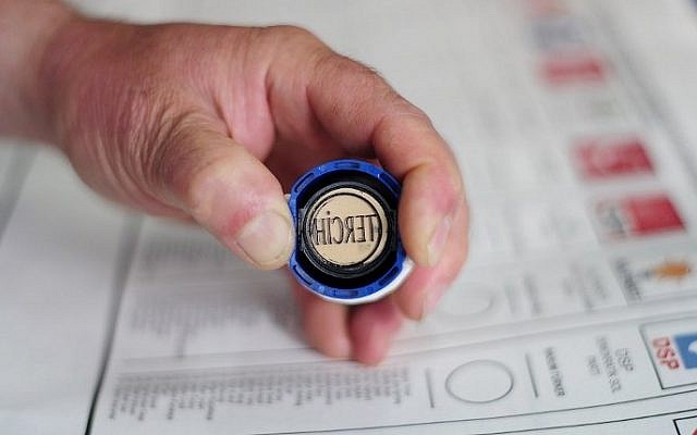 A man holds a stamp with party's sign above a vote ballot during Turkey's general election at a polling station in Istanbul, June 7, 2015. (AFP/OZAN KOSE)