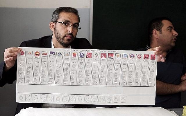 An elector officer holds a ballot with party signs during Turkey's general election at a polling station in Istanbul on June 7, 2015. (AFP/OZAN KOSE)